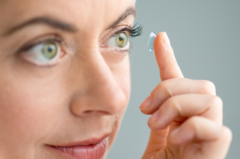 Kobieta aplikuje soczewki kontaktowe do oczu.